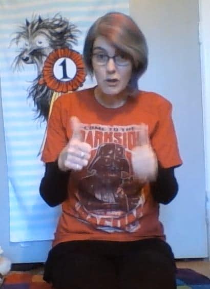 Anne doing online storytime, wearing a Star Wars Darth Vader tshirt: welcome to the dark side, we have bacon.