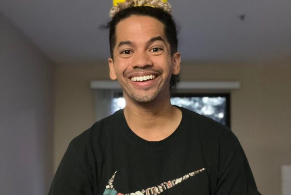 Mr. Mychal in a yellow crown and a black t-shirt that says: Just Read It