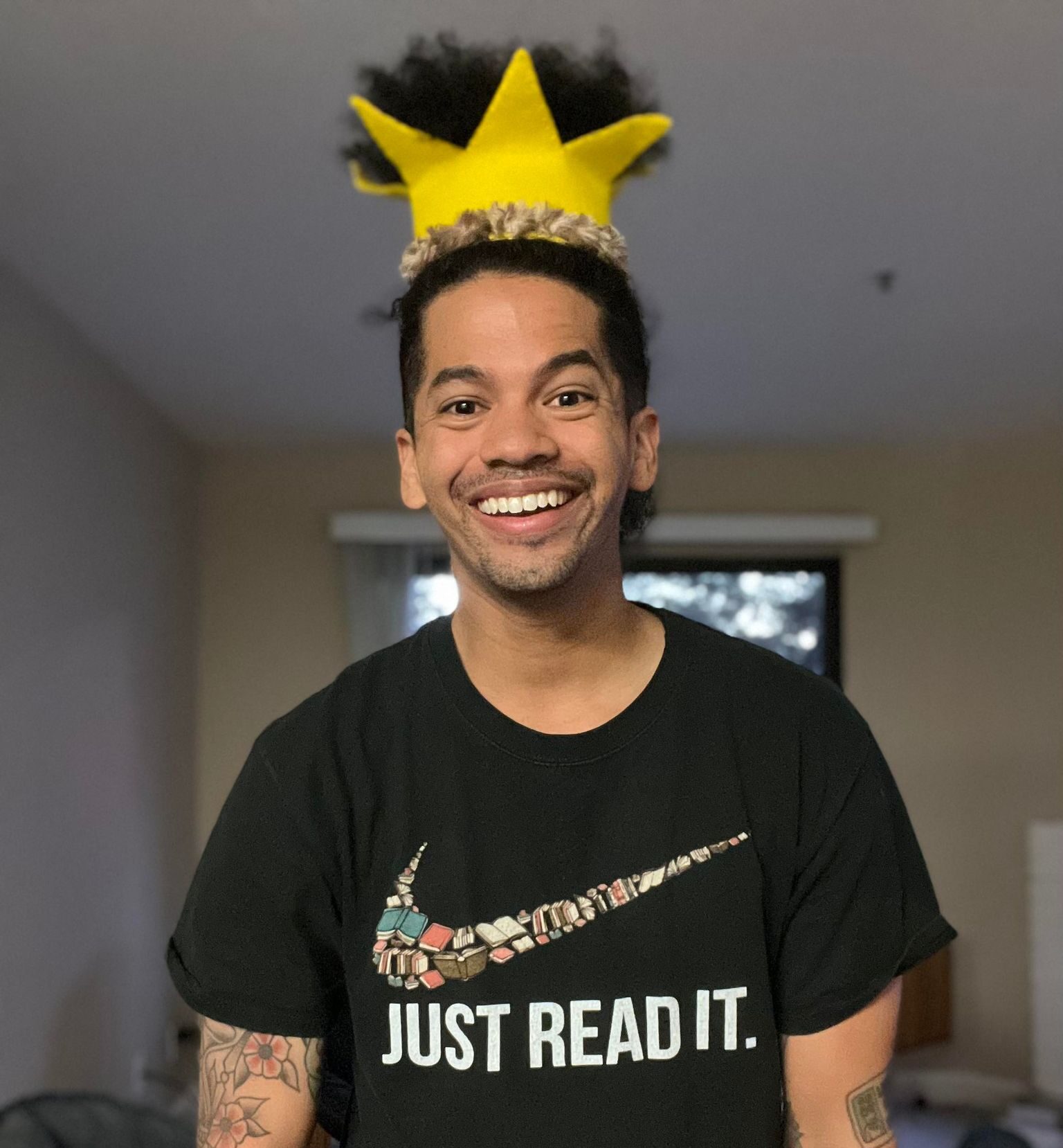 Mr. Mychal in a yellow crown and a black t-shirt that says: Just Read It